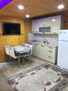 a kitchen with a table and a white refrigerator at New toprak suite in Uzungöl