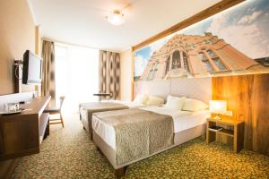 a hotel room with a large bed and a desk at Aranyhomok Business-City-Wellness Hotel in Kecskemét