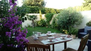 une table avec des tasses et des soucoupes dans un jardin dans l'établissement L'Hibiscus Chambre d'Hôte, à Avignon