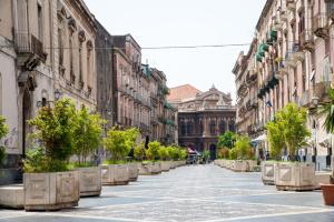 een lege straat met bomen en gebouwen bij Homes4Holidays - Teatro Massimo in Catania