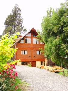 a large wooden building with trees and flowers at Cabaña Maitén in San Carlos de Bariloche