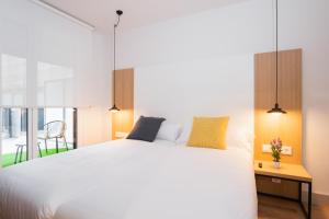 1 dormitorio con 1 cama blanca grande y balcón en Pensión Arroka, en San Sebastián