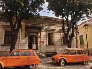 twee oranje auto's geparkeerd voor een gebouw bij Balkan Soul Hostel in Belgrado