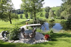 a patio with a table and chairs next to a pond at Moosmühle Allgäu in Untrasried