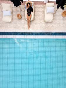 a woman sitting in a bed next to a swimming pool at Akra Morea Hotel & Residences in Monemvasia