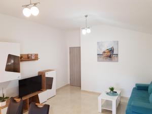 sala de estar con sofá azul y TV en Apartman Andrea en Zadar