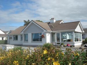 a white house with windows and flowers at Edenvale Bed & Breakfast in Portnoo