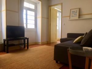 a living room with a couch and a tv at Sant'Ana Guest House in Leiria