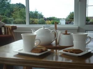 a table with tea cups and cookies on plates at Edenvale Bed & Breakfast in Portnoo