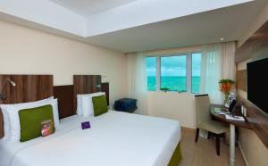 a hotel room with a bed and a desk and a window at Mercure Maceio Pajuçara in Maceió