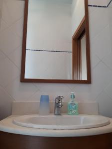 ein Waschbecken mit einem Spiegel und einer Flasche Seife in der Unterkunft Il Mirto in Viareggio