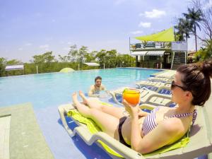 Una donna seduta su una zattera in piscina con un drink di Rumors Resort Hotel a San Ignacio