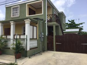 a green house with a fence in front of it at Believe Caribbean Apartment in Bridgetown