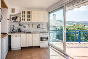 a kitchen with white cabinets and a large window at Spiti Ena in Theológos