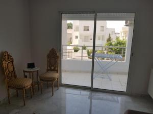 a room with two chairs and a sliding glass door at Appartement S+1 Jardin De Carthage in Tunis