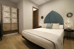 1 dormitorio con 1 cama blanca grande y cabecero azul en AbraCadabra Suites, en Madrid