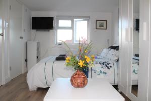 um quarto com uma cama e um vaso com flores sobre uma mesa em Jing's Loft Converted Studio em Edmonton