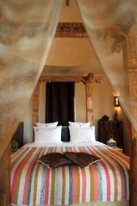 - une chambre avec un grand lit à baldaquin dans l'établissement O'Atlas, à El Harkat