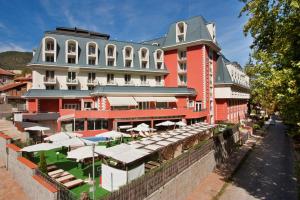 un grand bâtiment rouge avec des tables et des parasols devant lui dans l'établissement Balneo Complex & Spa Aquatonik, à Velingrad