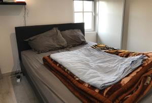 an unmade bed with a blanket and pillows on it at Appartement Hyper centre Silencieux Lumineux in Dreux