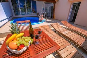 a picnic table with a bowl of fruit and a bottle of wine at Vila Izabela in Stara Novalja