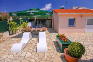 a patio with two white benches and a green umbrella at Vila Izabela in Stara Novalja