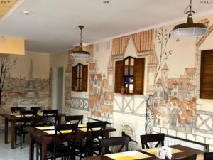 a restaurant with tables and chairs and a mural at Турист in Uman