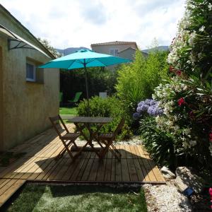 einen Tisch und Stühle mit einem Sonnenschirm auf einer Terrasse in der Unterkunft 2 pièces indépendant avec son jardinet privé in Borgo