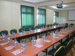 una fila di tavoli e sedie in una stanza con bottiglie d'acqua di Ash White Hotel a Nairobi