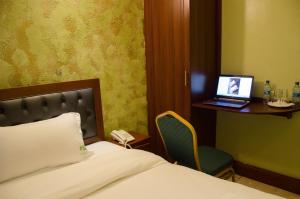 內羅畢的住宿－白灰酒店，一间卧室配有一张床和一张桌子上的笔记本电脑