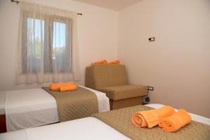 a bedroom with two beds and a chair and a window at Apartment Markioli in Povlja