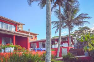 a red house with palm trees in front of it at Pousada Canto da Brava in Balneário Camboriú