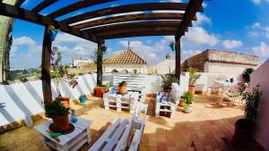 un patio con sillas y mesas blancas y un edificio en Casa Mirador San Pedro, en Arcos de la Frontera