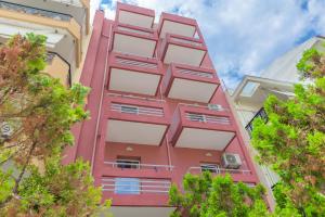 a pink building with trees in front of it at Marinas Apartments Alexandroupolis in Alexandroupoli