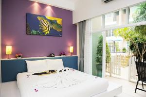 a bedroom with a white bed with a painting on the wall at The Beach Boutique House in Kata Beach +84 photos