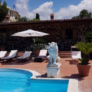 uma estátua ao lado de uma piscina com um guarda-sol em L'Oasi di Ambra Dependance em Ardea