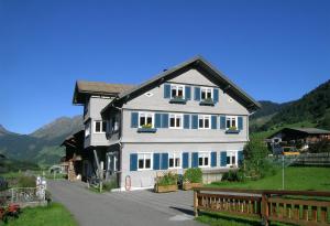 a large white house with blue windows and a fence at Bauernhof Madlener Claudia in Schoppernau