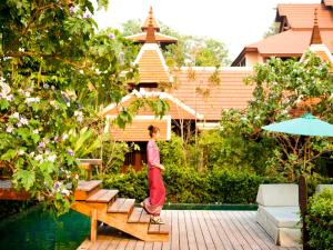 a woman walking on a wooden platform in a garden at Siripanna Villa Resort & Spa Chiang Mai -SHA Extra Plus in Chiang Mai
