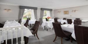 恩布爾頓的住宿－The Dunstanburgh Castle Hotel，一间设有白色桌椅的用餐室