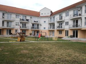 um grande edifício de apartamentos com um parque infantil no quintal em Freedom Apartman em Hajdúszoboszló