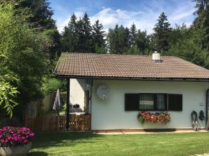 una pequeña casa blanca con una ventana y flores en Ferienbungalow Weber, en Velden am Wörthersee