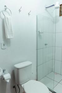 a bathroom with a toilet and a glass shower at Casa Azul Caraíva - Casas Do San in Caraíva