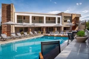 a swimming pool with chairs and umbrellas next to a building at KB Ammos in Skiathos Town