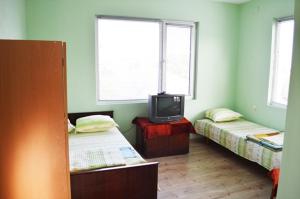 a room with two beds and a tv in it at Къща за гости "Черната роза" in Bŭlgarevo
