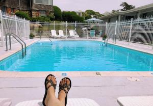 a person with their feet up next to a swimming pool at Sands Of Time Motor Inn & Harbor House in Woods Hole