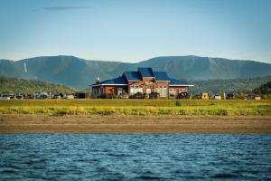 a house by the water with mountains in the background at Chalets Valmont in Cap-Chat