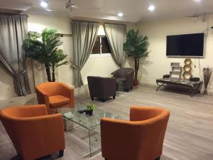a living room with orange chairs and a tv at Wahat Al Yarmouk Serviced Apartments in Ţubarjal