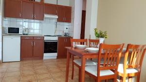 cocina con mesa de madera y sillas de madera en Laci Apartman, en Zalakaros
