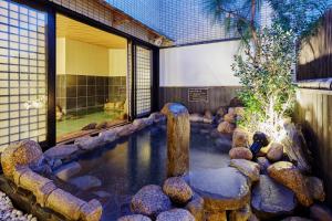 una piscina d'acqua con rocce di fronte a un edificio di Dormy Inn Kurashiki Natural Hot Spring a Kurashiki