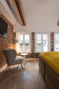 a bedroom with a bed and a chair and windows at Square Rooms 20 in Düsseldorf